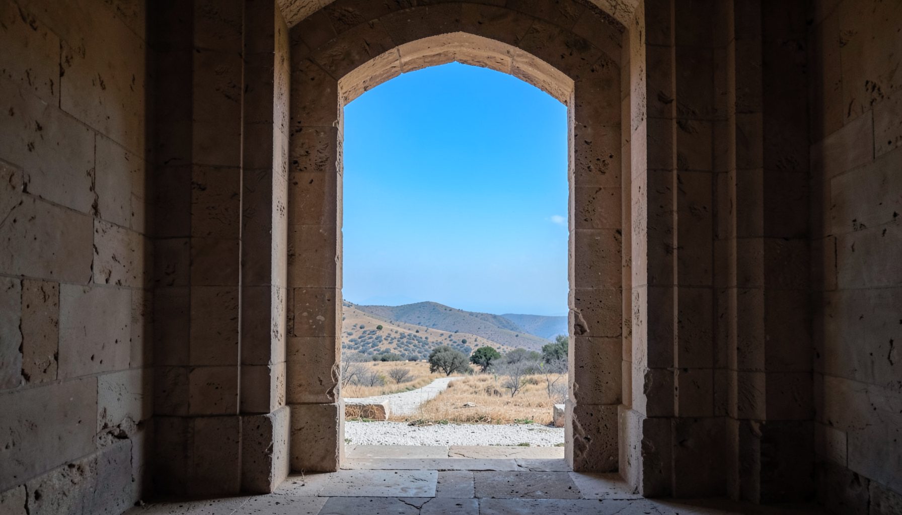A serene architectural detail of an ancient stone archway framing a distant landscape, muted earth tones and soft natural light