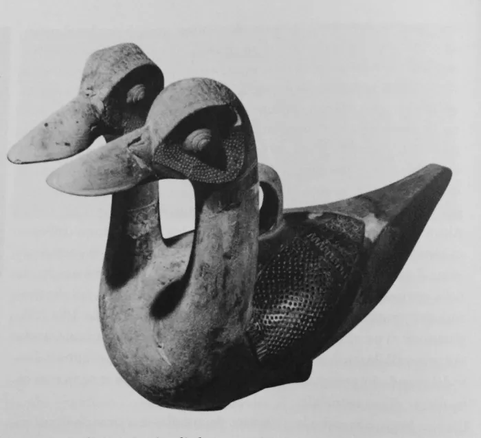 Black and white photo of a carved artifact shaped like two bird heads joined together